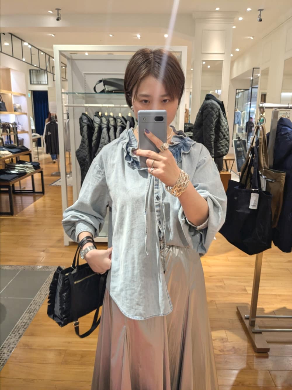 シルバー系のスカート、ブルー系のシャツ/ブラウス、ブラック系のショルダーバッグを着用したレディースの冬コーディネートの10枚目の写真