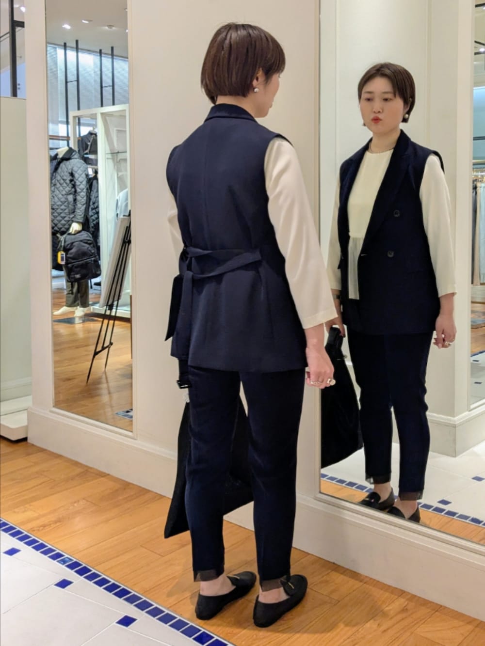 ホワイト系のシャツ/ブラウス、ブルー系のベスト、ブラック系のショルダーバッグを着用したレディースの冬コーディネートの7枚目の写真