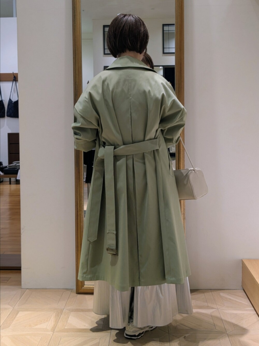 シルバー系のスカート、ブルー系のカーディガン/ボレロ、グリーン系のトレンチコートを着用したレディースの冬コーディネートの5枚目の写真