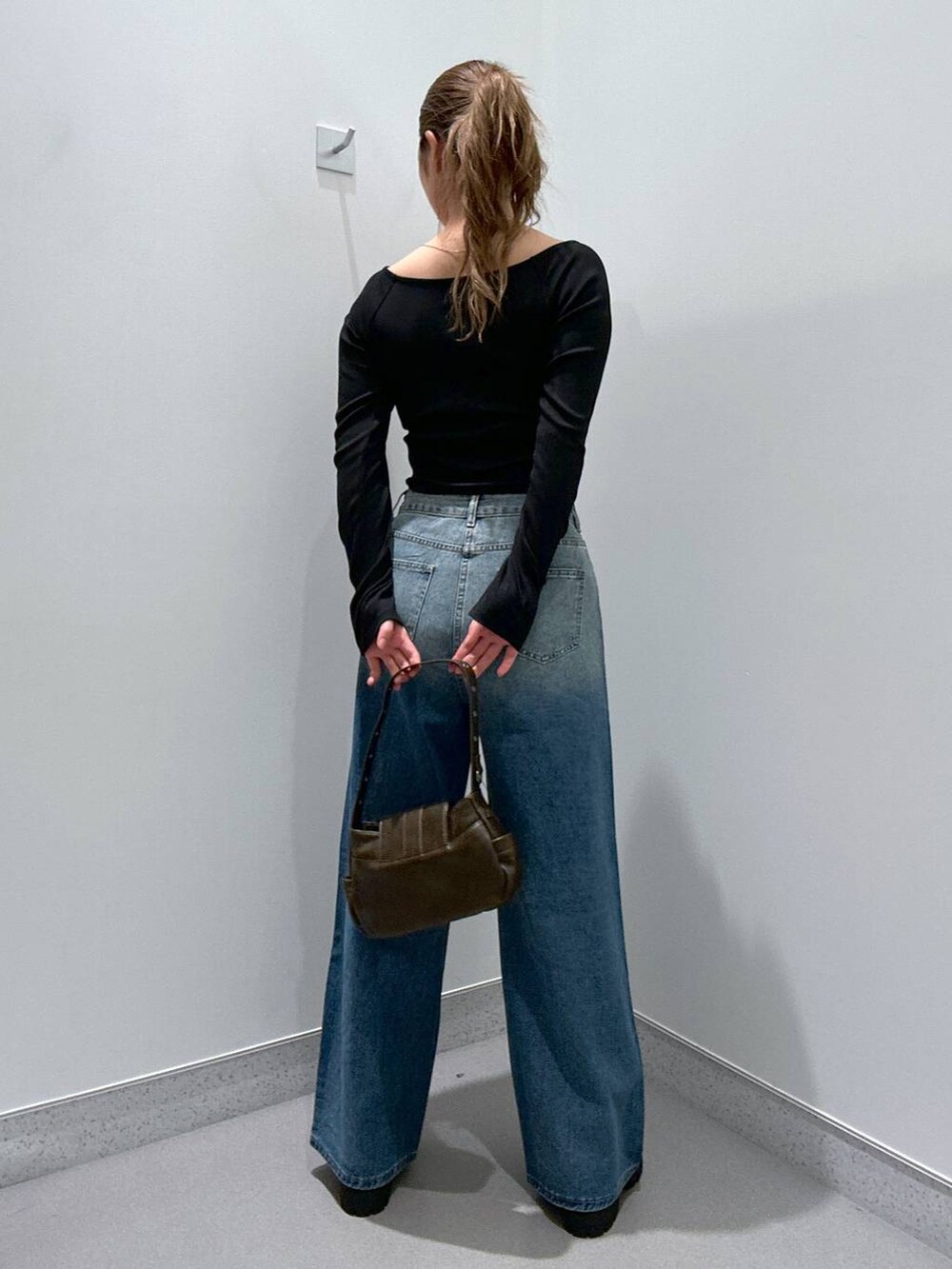 ブルー系のデニムパンツ、ブラウン系のローファー、ブラック系のTシャツ/カットソーを着用したレディースの冬コーディネートの3枚目の写真