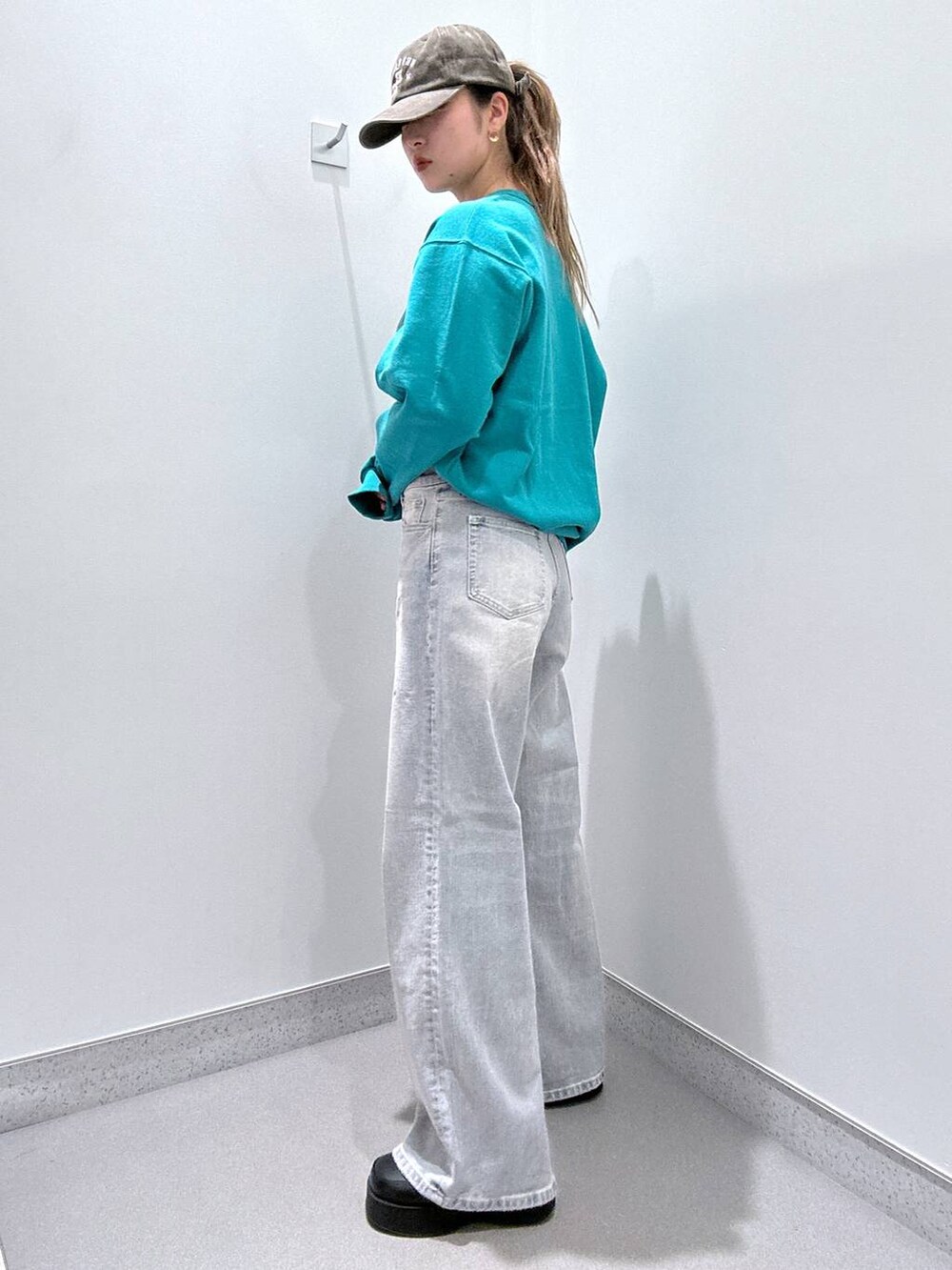 ブラック系のスリッポン、グリーン系のスウェット、ブルー系のデニムパンツを着用したレディースの冬コーディネートの2枚目の写真