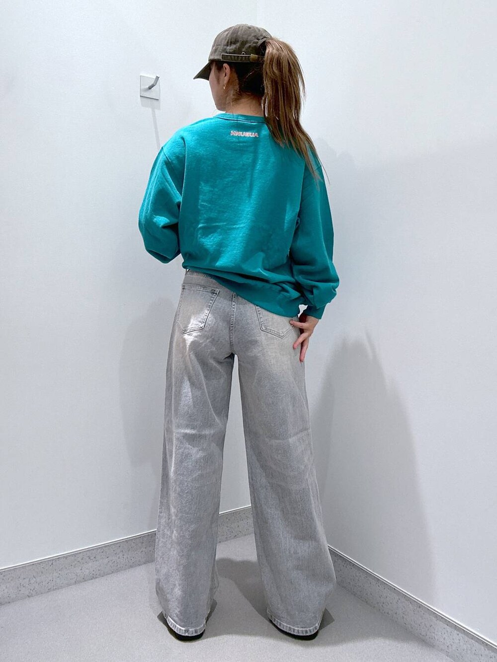 ブラック系のスリッポン、グリーン系のスウェット、ブルー系のデニムパンツを着用したレディースの冬コーディネートの3枚目の写真