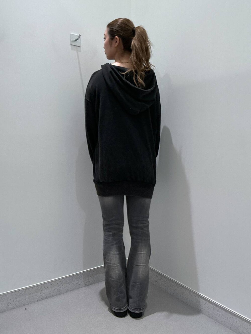 グレー系のデニムパンツ、ブラウン系のローファー、ブラック系のパーカーを着用したレディースの冬コーディネートの3枚目の写真