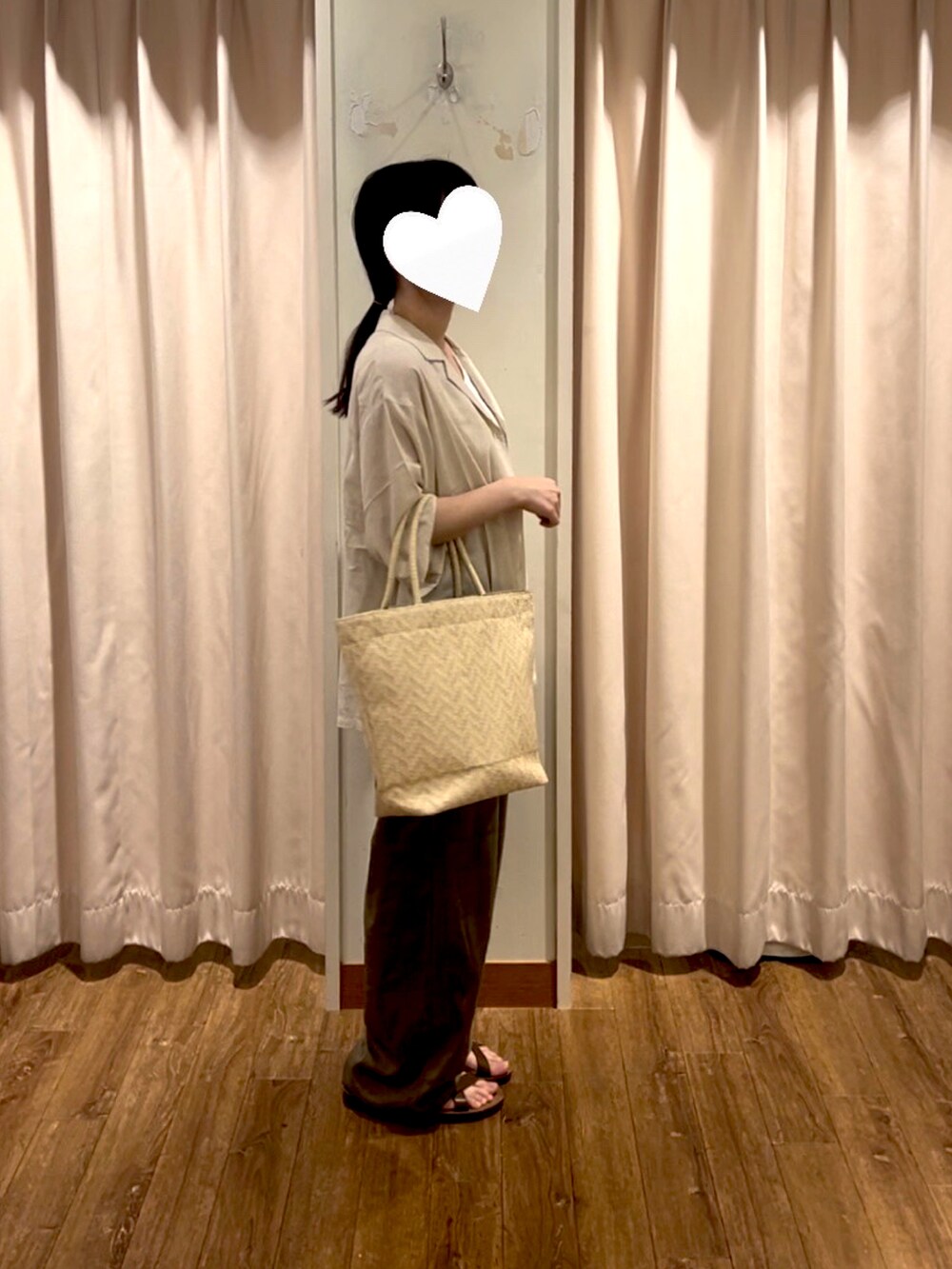 ホワイト系のハンドバッグ、ホワイト系のタンクトップ、ブラウン系のパンツを着用したレディースの夏コーディネートの2枚目の写真