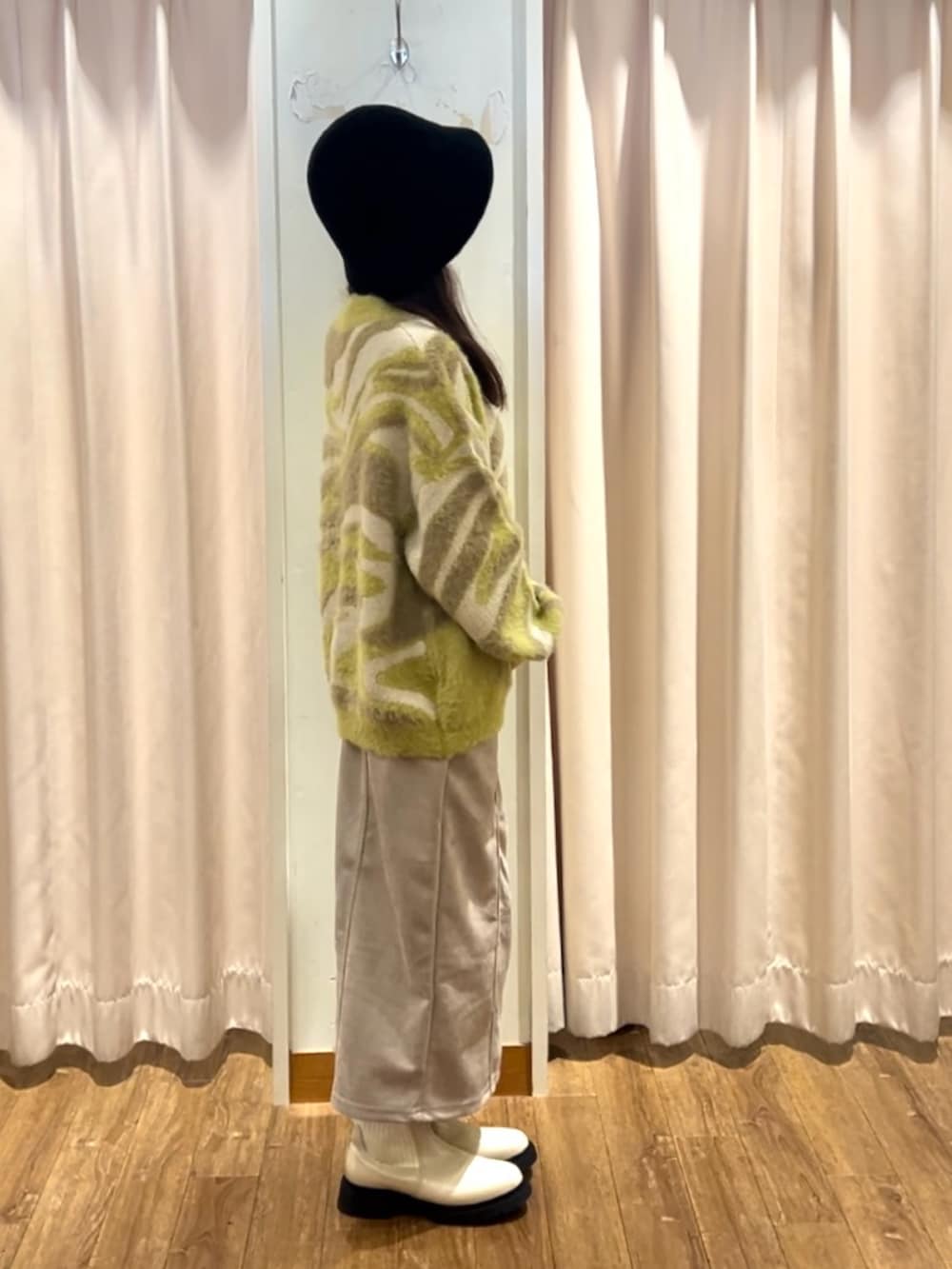 イエロー系のニット/セーター、ベージュ系のスカート、ベージュ系のブーツを着用したレディースの秋コーディネートの2枚目の写真