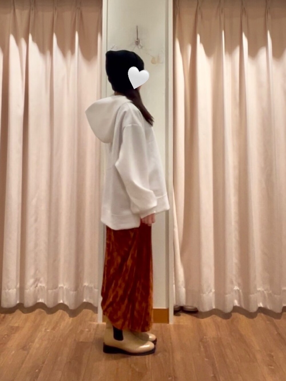 オレンジ系のスカート、ベージュ系のブーツ、ブラック系のハットを着用したレディースの冬コーディネートの2枚目の写真