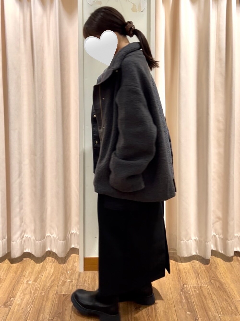 ブラック系のスカート、ブラック系のブーツ、ブラック系のハンドバッグを着用したレディースの秋コーディネートの2枚目の写真