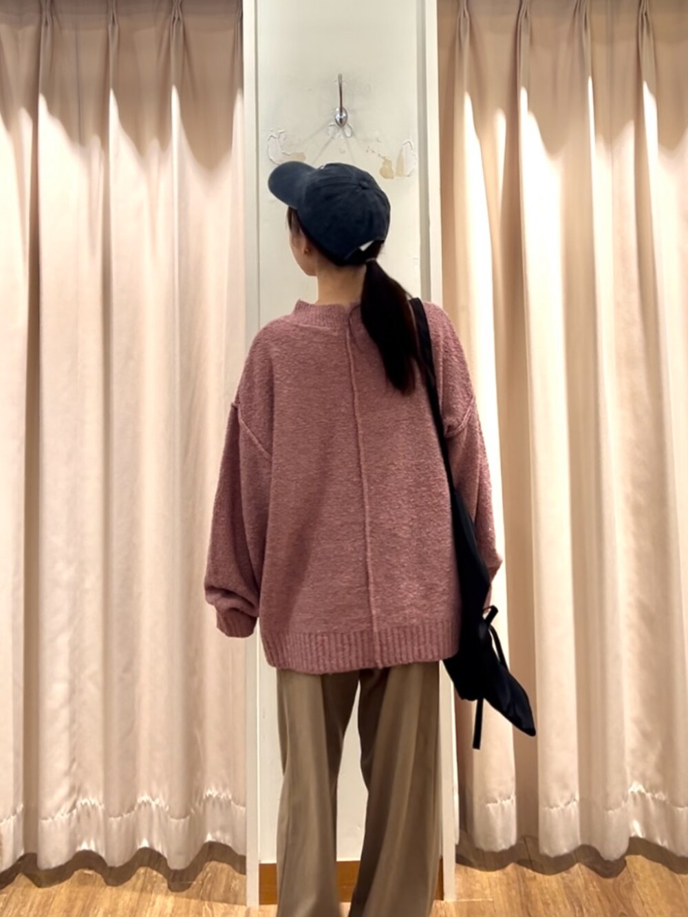 グレー系のドレスシューズ、ブラック系のハンドバッグ、ピンク系のニット/セーターを着用したレディースの秋コーディネートの3枚目の写真