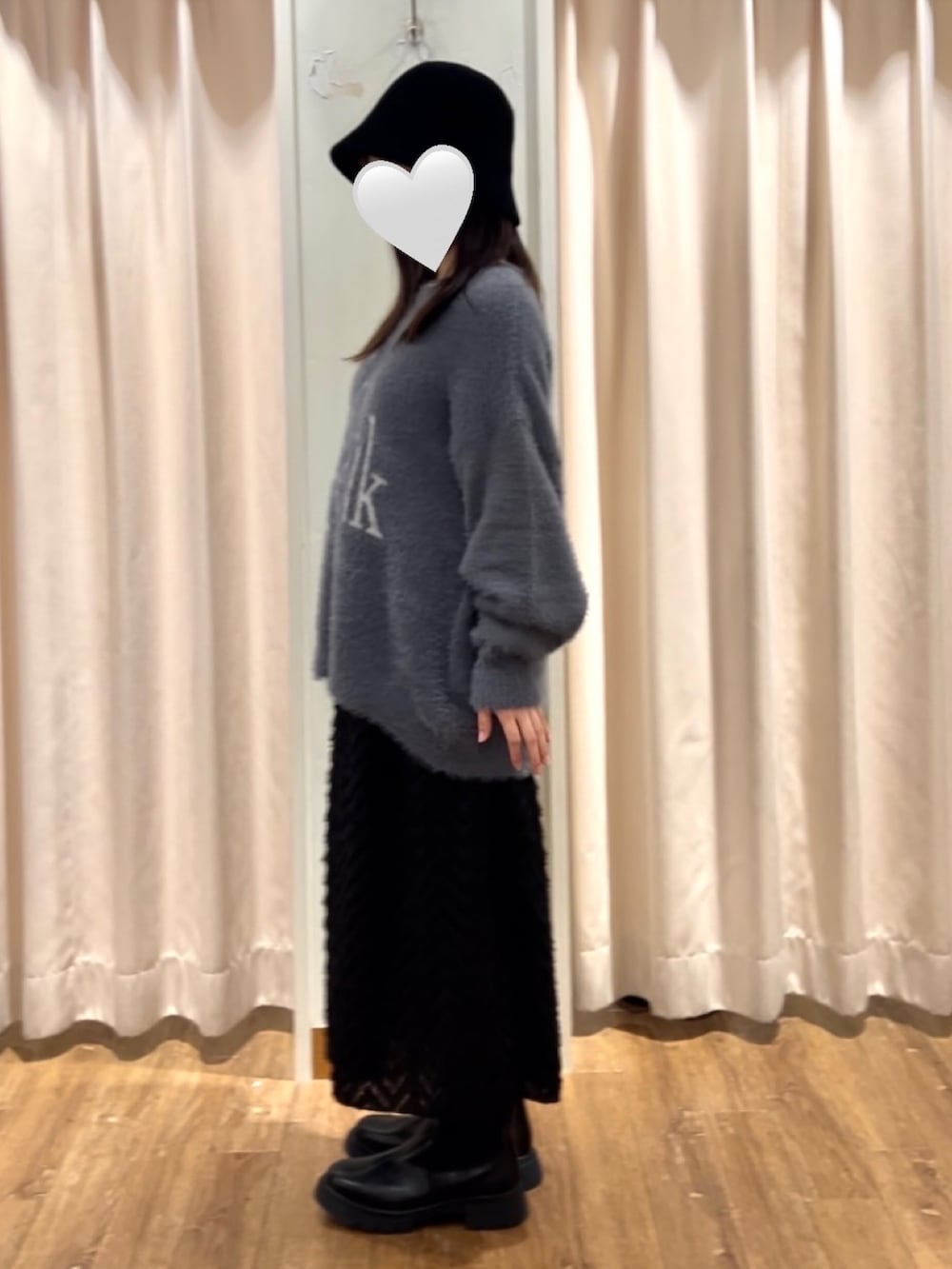 グレー系のニット/セーター、ブラック系のスカート、ブラック系のブーツを着用したレディースの秋コーディネートの2枚目の写真