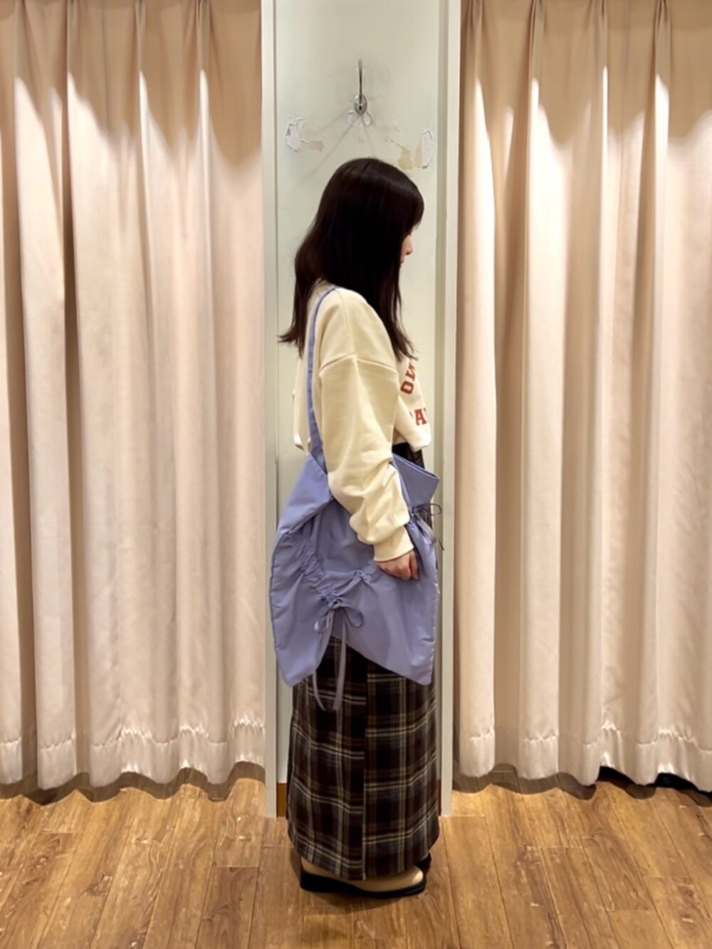 ブラウン系のスカート、ベージュ系のブーツ、パープル系のハンドバッグを着用したレディースの秋コーディネートの2枚目の写真