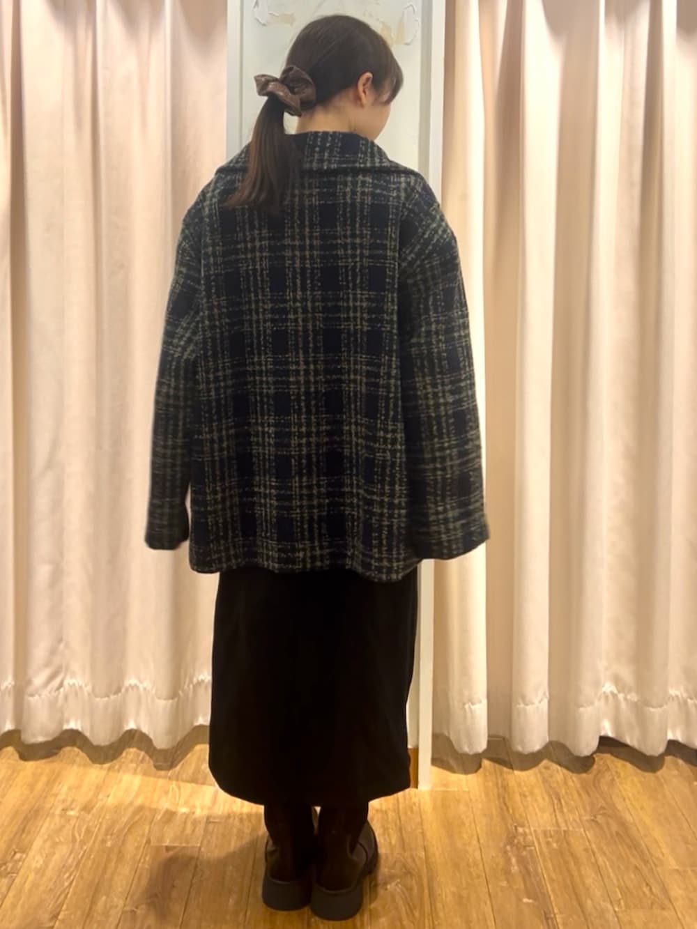 ブラック系のブーツ、ブラック系のスカート、ホワイト系のニット/セーターを着用したレディースの秋コーディネートの3枚目の写真