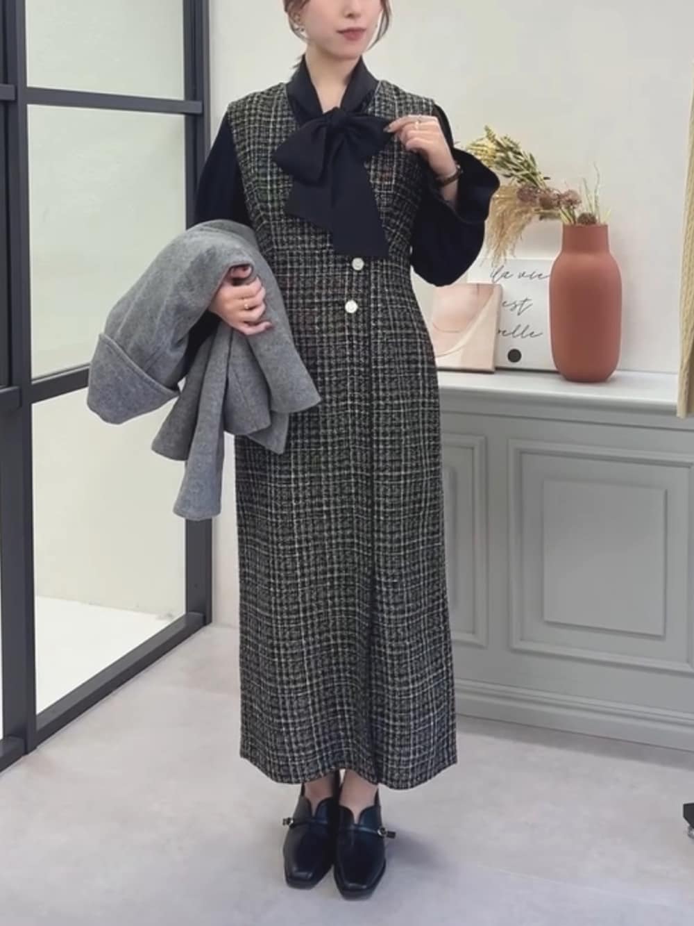 ブラック系のシャツ/ブラウス、ブラック系のジャンパースカート、グレー系のチェスターコートを着用したレディースの冬コーディネートの3枚目の写真