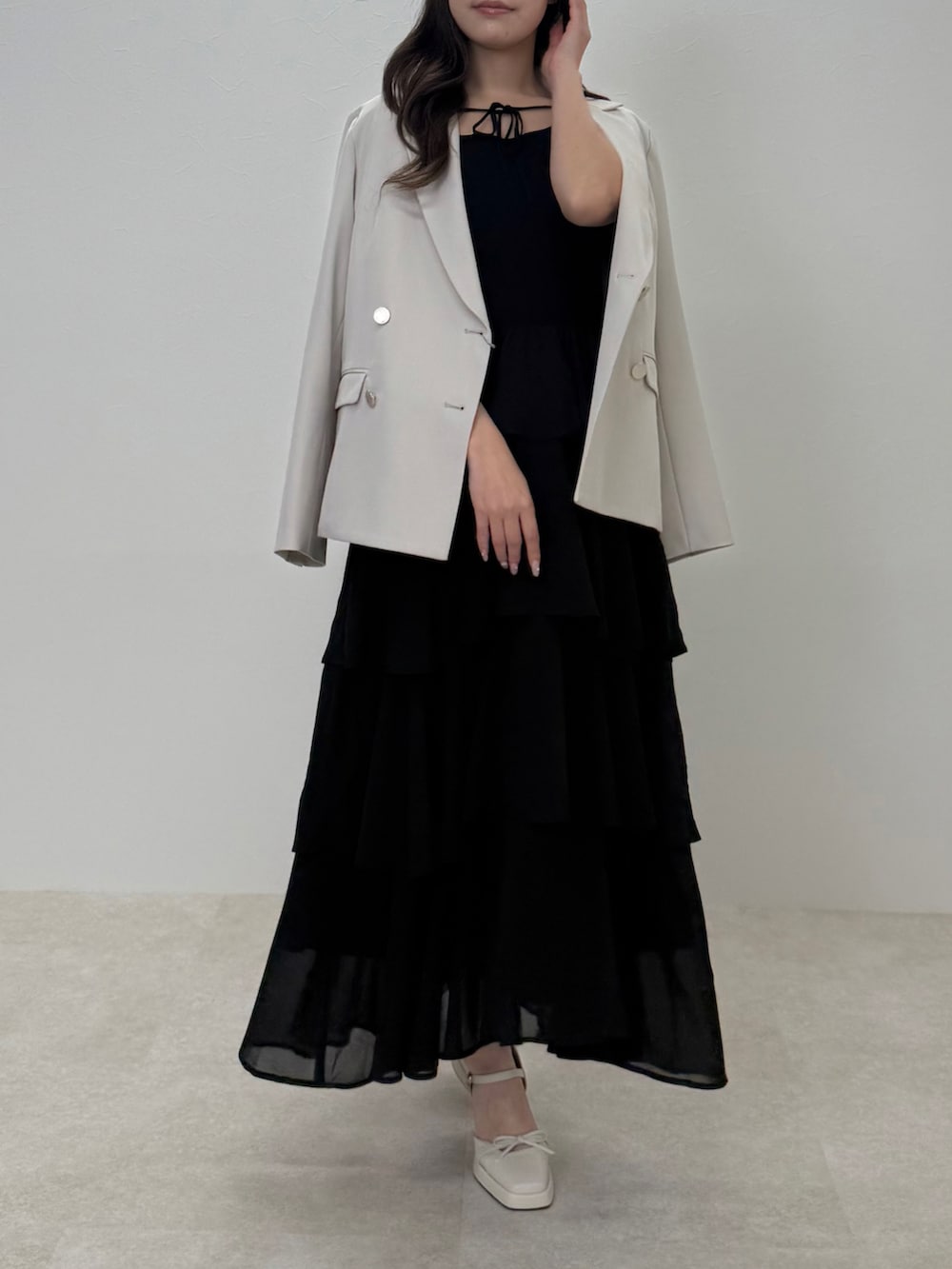 ブラック系のワンピース、ベージュ系のテーラードジャケットを着用したレディースの春コーディネートの2枚目の写真