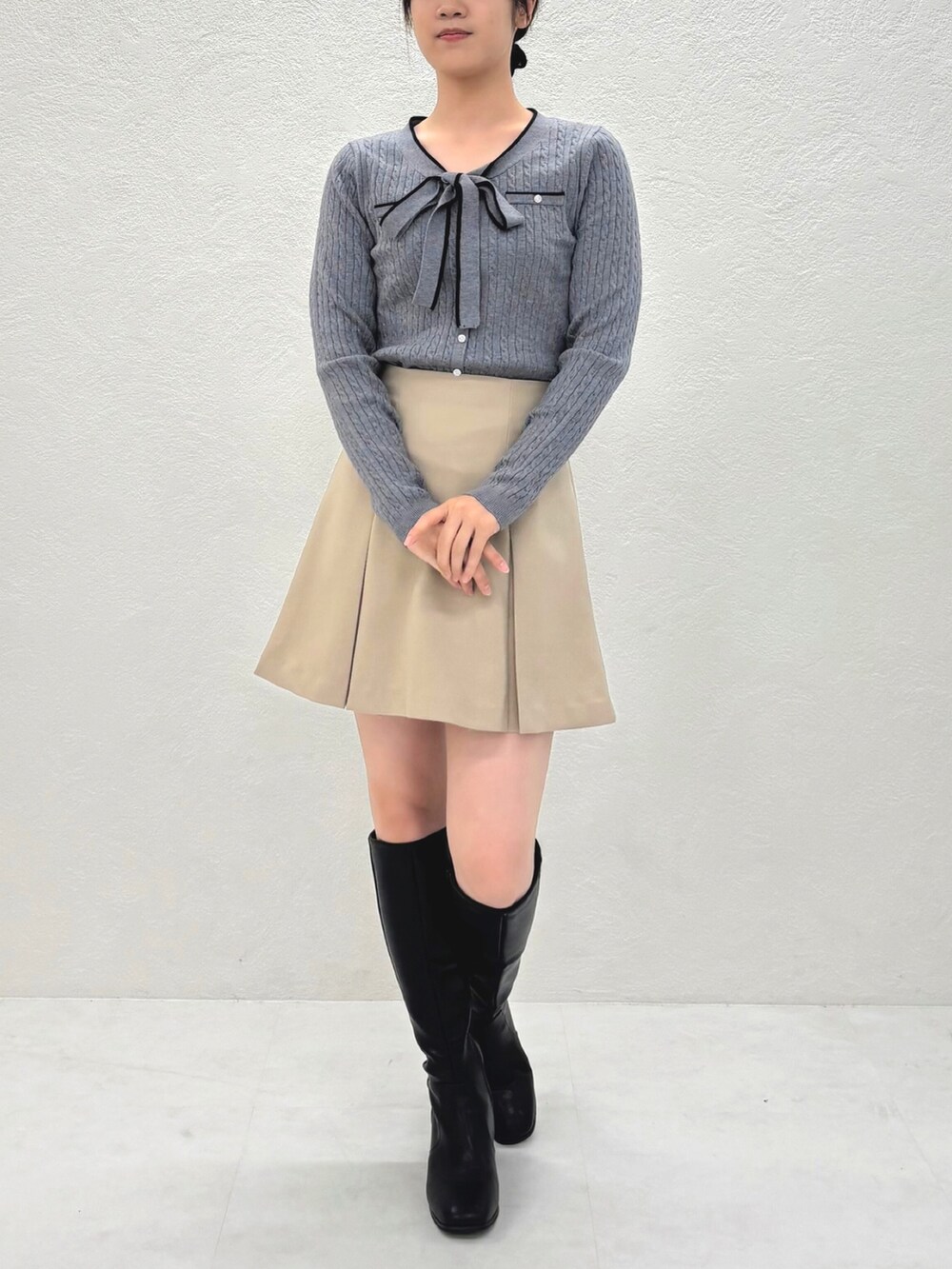 ベージュ系のスカート、グレー系のニット/セーターを着用したレディースの秋コーディネートの2枚目の写真