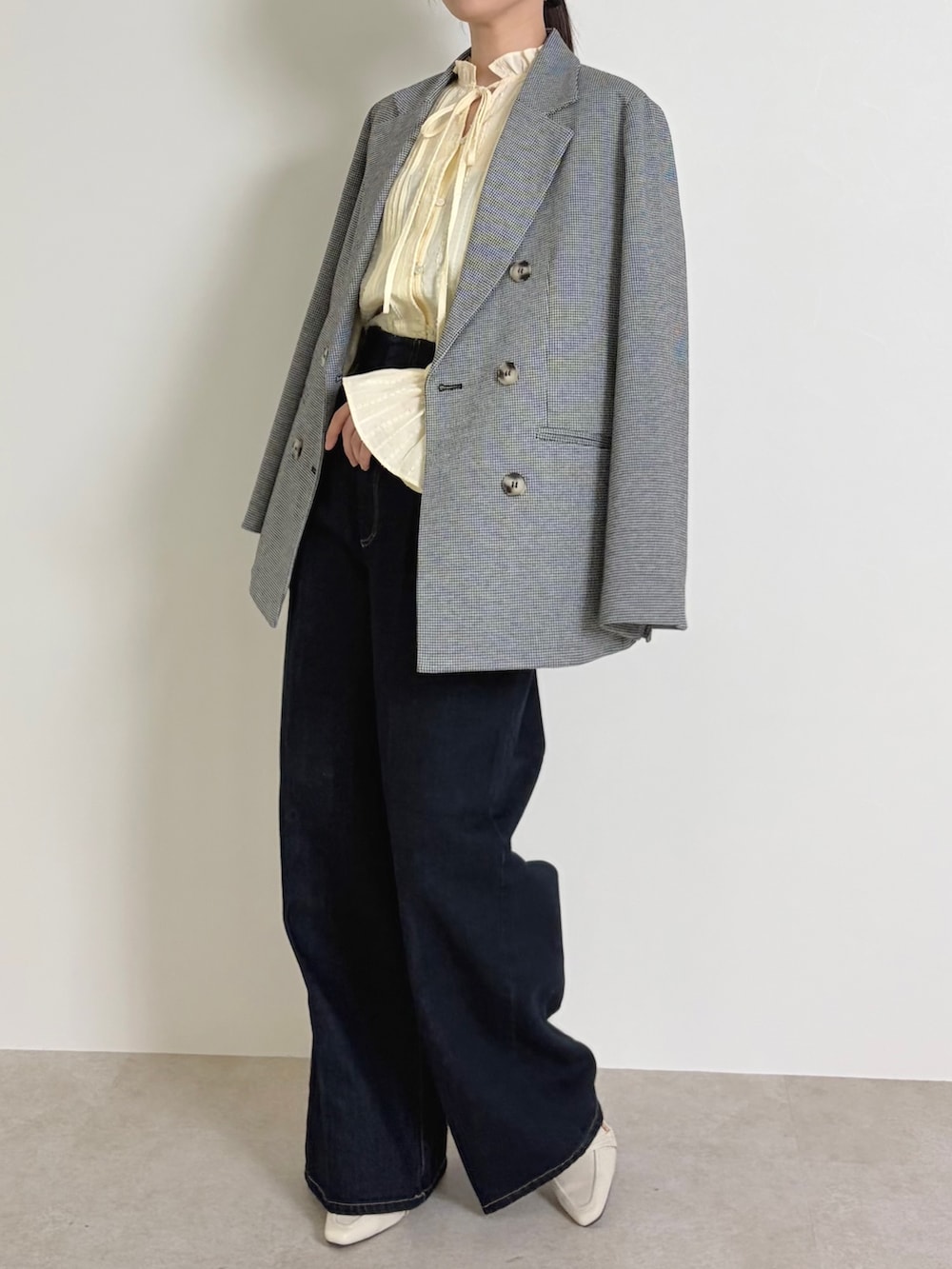 イエロー系のシャツ/ブラウス、ブラック系のテーラードジャケット、ブルー系のデニムパンツを着用したレディースの春コーディネートの3枚目の写真