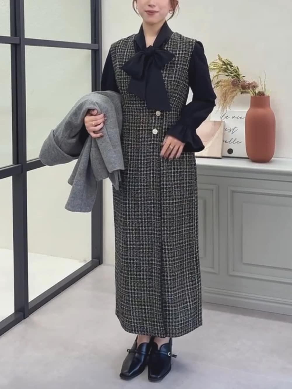 ブラック系のシャツ/ブラウス、ブラック系のジャンパースカート、グレー系のチェスターコートを着用したレディースの冬コーディネートの2枚目の写真