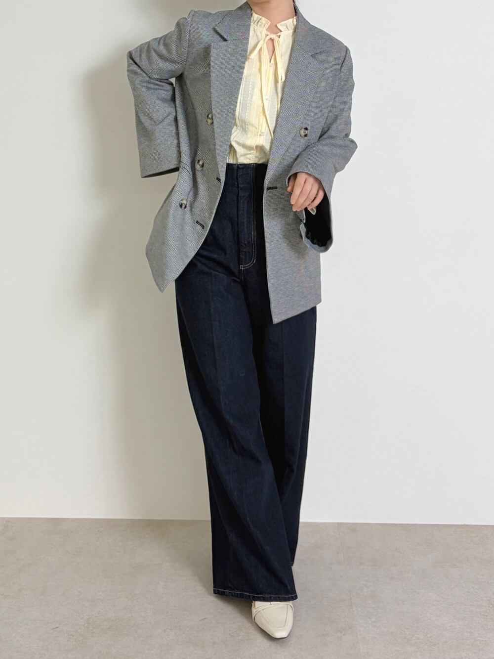 イエロー系のシャツ/ブラウス、ブラック系のテーラードジャケット、ブルー系のデニムパンツを着用したレディースの春コーディネートの4枚目の写真