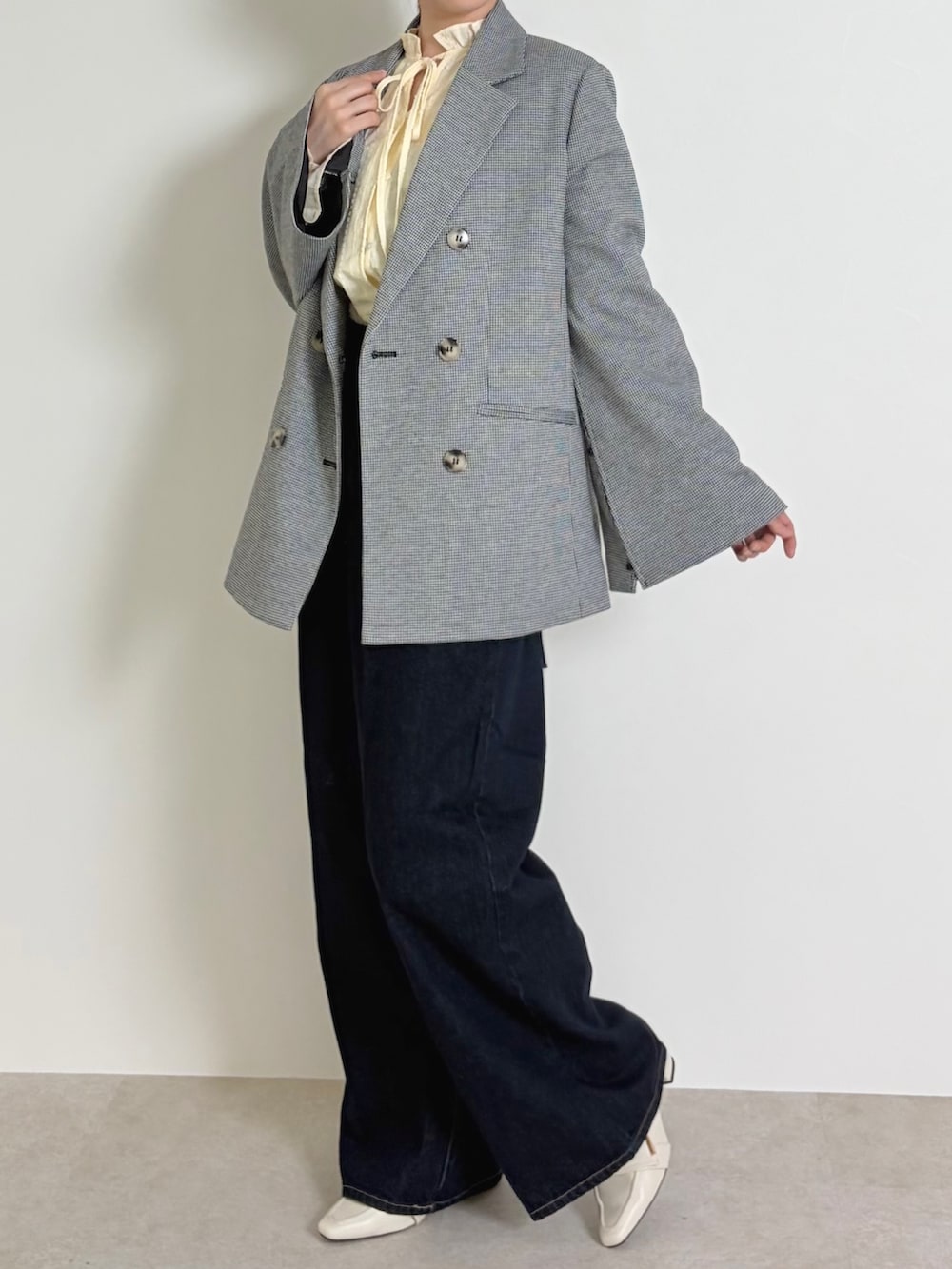 イエロー系のシャツ/ブラウス、ブラック系のテーラードジャケット、ブルー系のデニムパンツを着用したレディースの春コーディネートの2枚目の写真