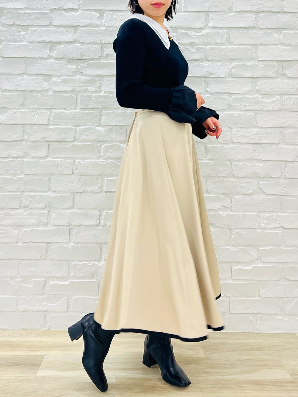 ブラック系のニット/セーター、ベージュ系のスカートを着用したレディースの冬コーディネートの2枚目の写真