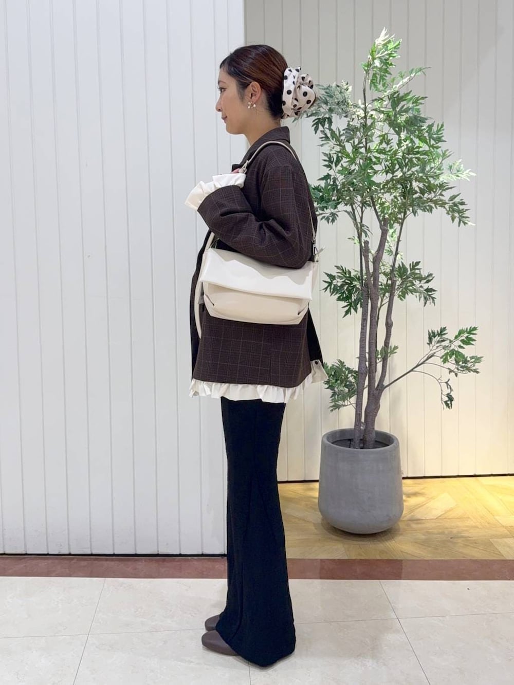 ホワイト系のショルダーバッグ、ブラウン系のブーツ、ホワイト系のTシャツ/カットソーを着用したレディースの秋コーディネートの2枚目の写真