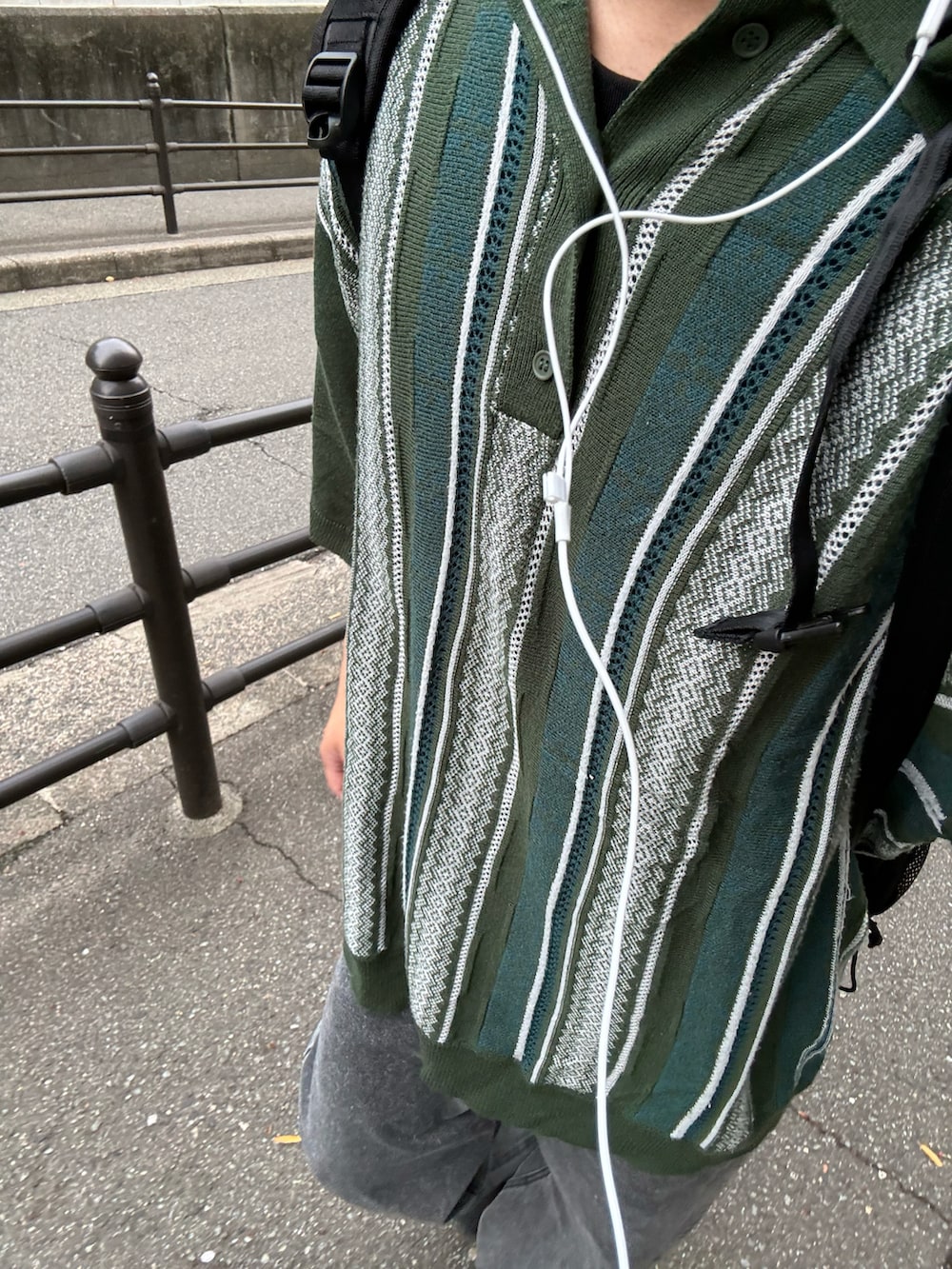 グレー系のデニムパンツ、グリーン系のポロシャツ、ブラック系のブーツを着用したメンズの春コーディネートの2枚目の写真