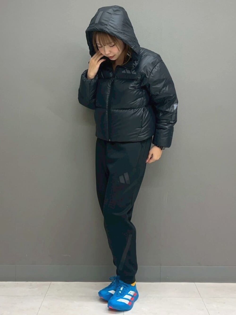 ブラック系のスウェットパンツ、ブルー系のシューズ、ホワイト系のショルダーバッグを着用したレディースの冬コーディネートの2枚目の写真