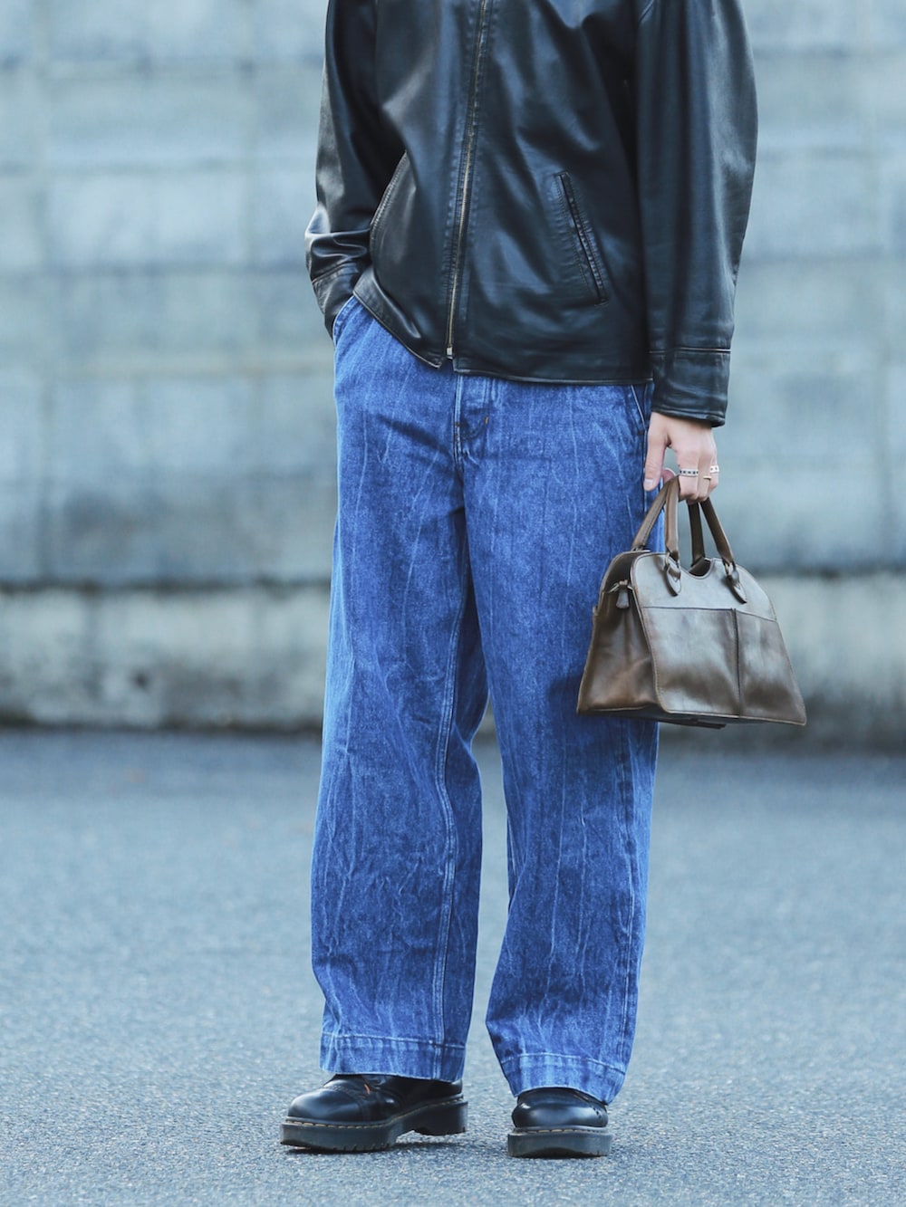 ブラック系のその他アウター、ブルー系のデニムパンツ、ブラウン系のハンドバッグを着用したメンズの秋コーディネートの3枚目の写真