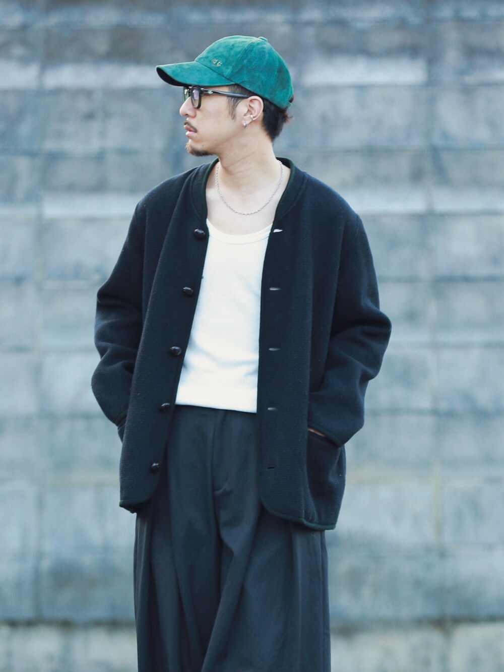 ブラック系のパンツ、ブラック系のシューズ、グリーン系のキャップを着用したメンズの秋コーディネートの2枚目の写真