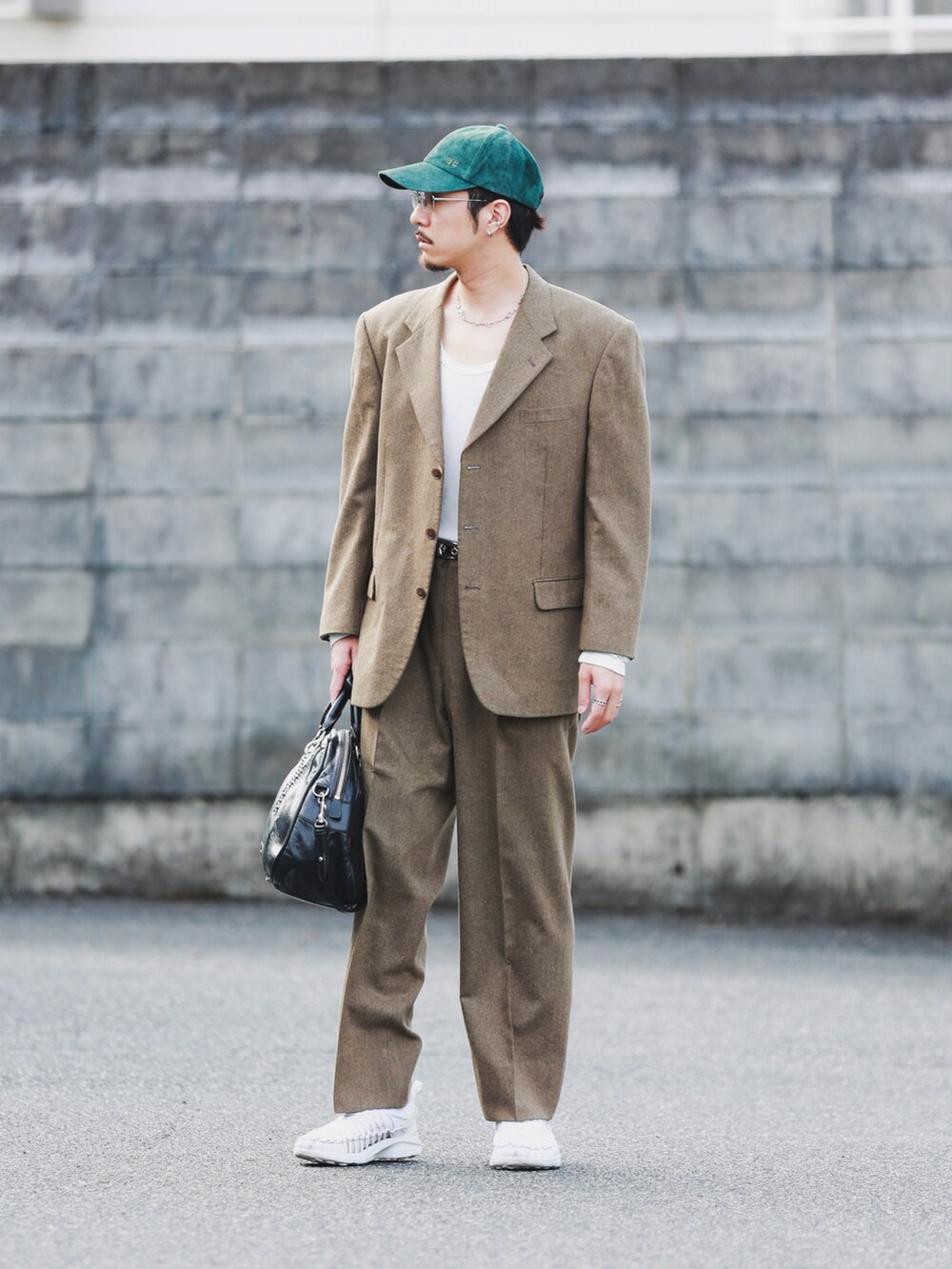 ブラック系のバッグ、ホワイト系のシューズ、シルバー系のメガネを着用したメンズの秋コーディネートの2枚目の写真