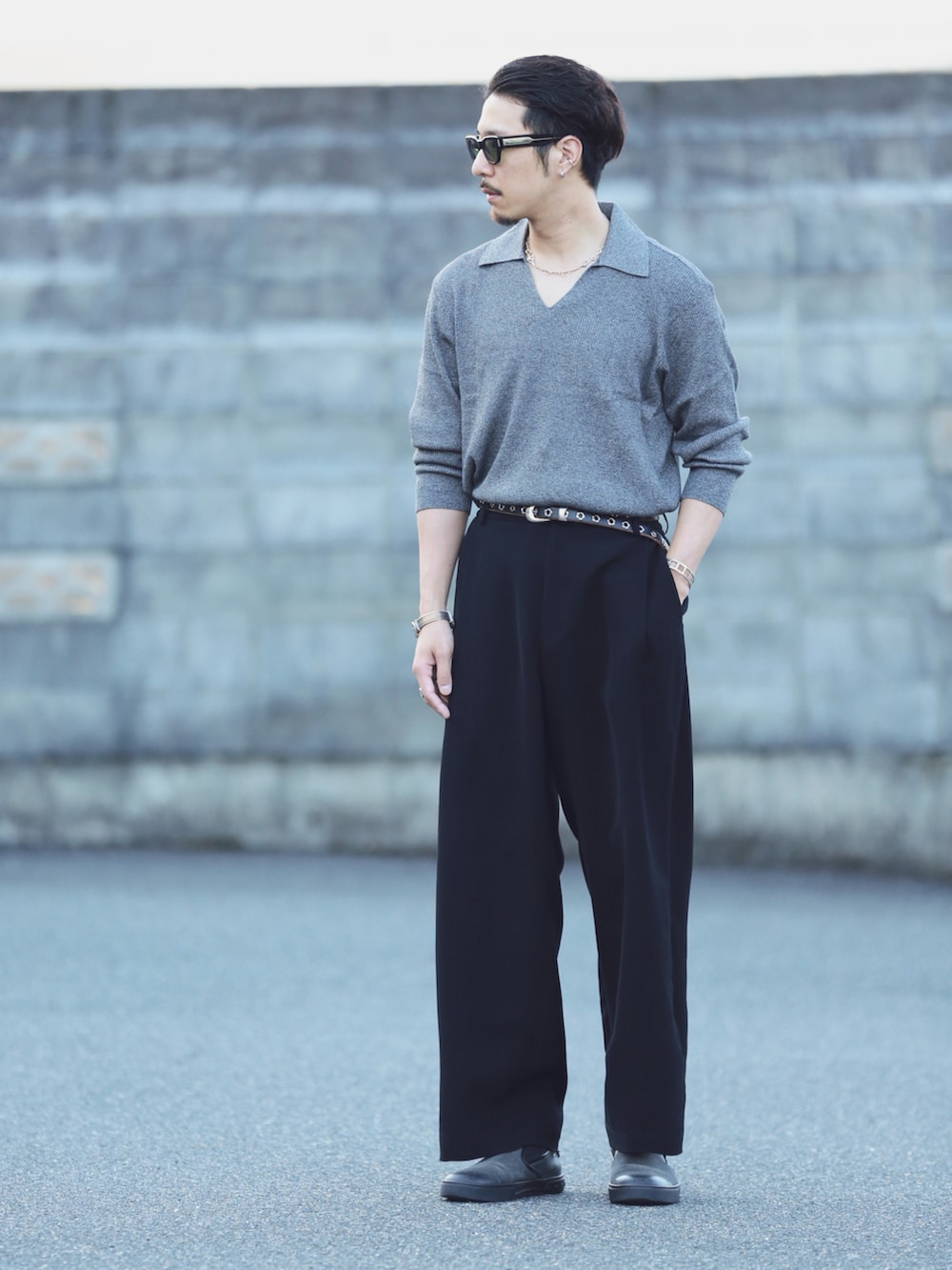 グレー系のニット/セーター、ブラック系のスラックス、グレー系のスリッポンを着用したメンズの秋コーディネートの2枚目の写真