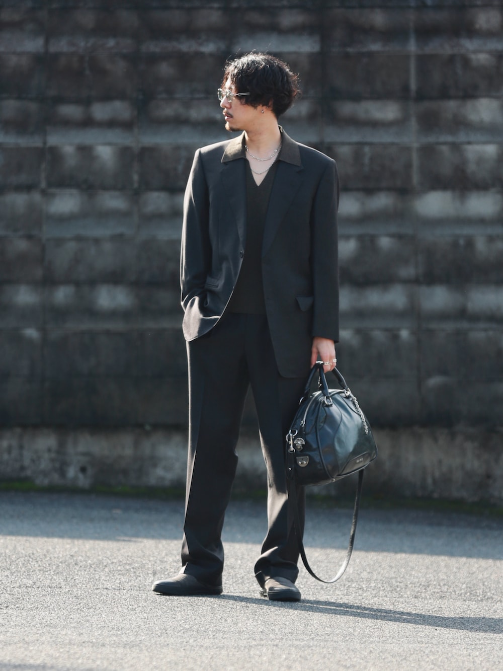 ブラウン系のニット/セーター、ブラック系のバッグ、グレー系のスリッポンを着用したメンズの冬コーディネートの3枚目の写真