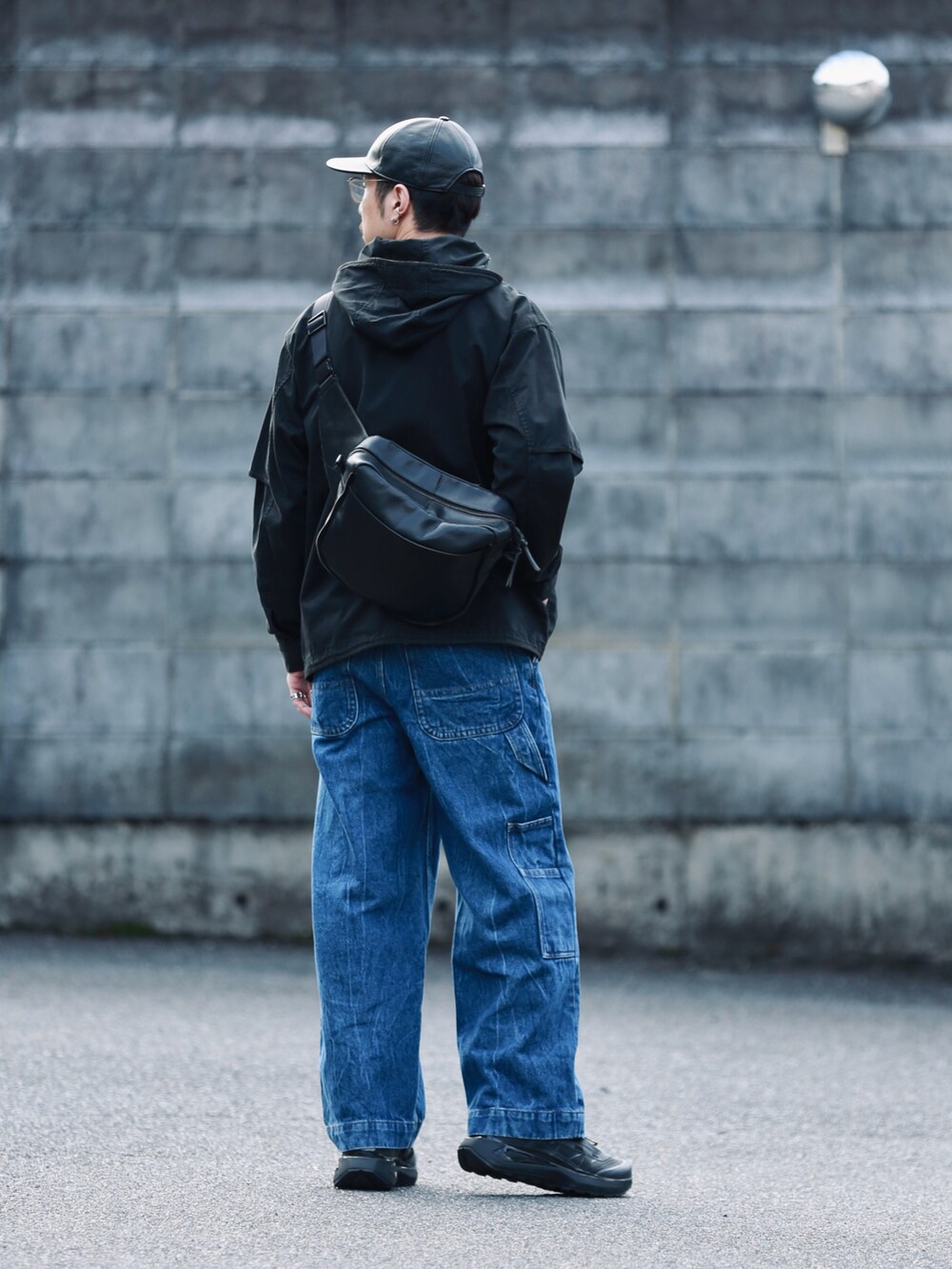ブルー系のデニムパンツ、ブラック系のショルダーバッグ、ブラック系のスニーカーを着用したメンズの秋コーディネートの3枚目の写真