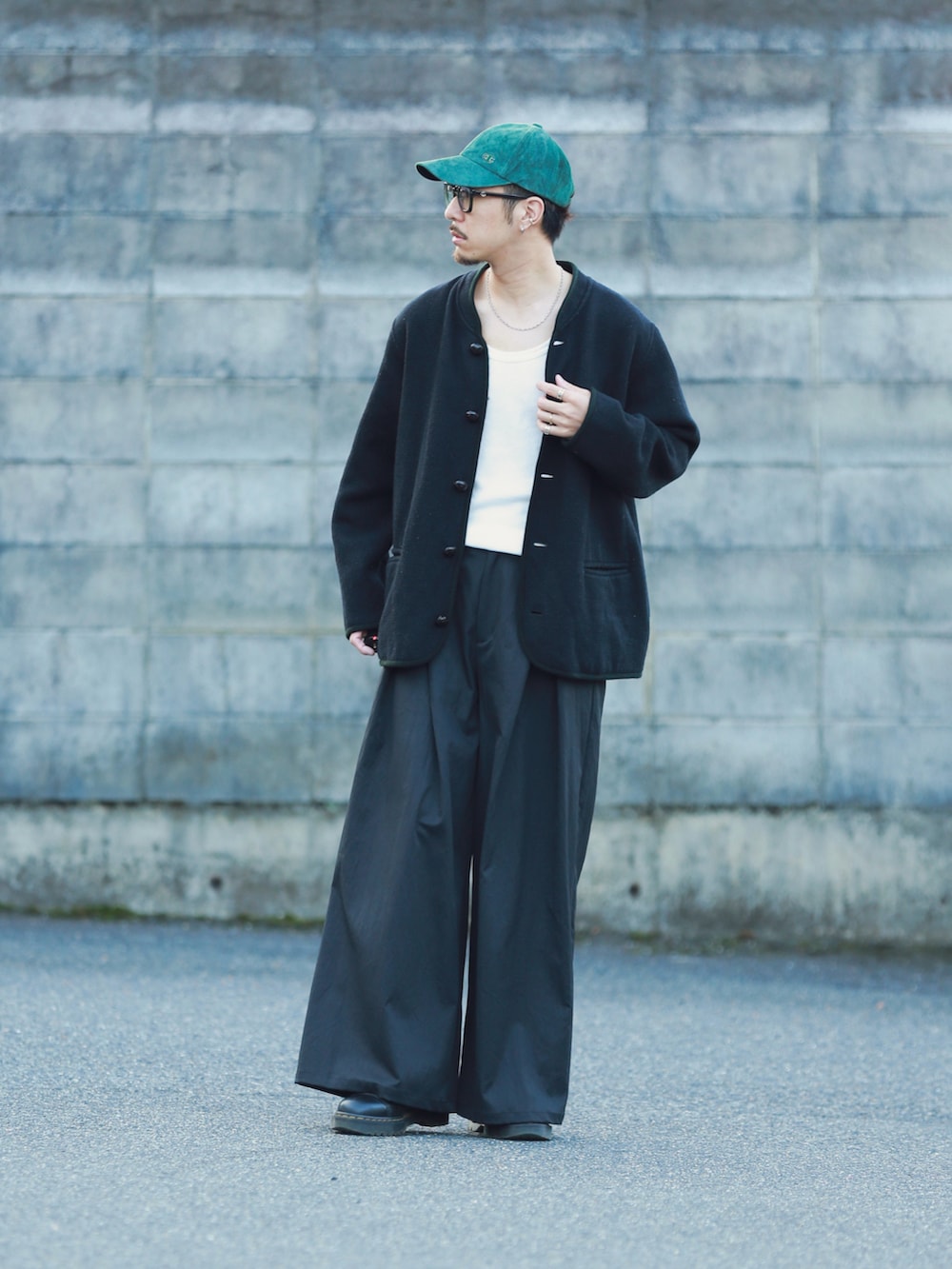ブラック系のパンツ、ブラック系のシューズ、グリーン系のキャップを着用したメンズの秋コーディネートの4枚目の写真
