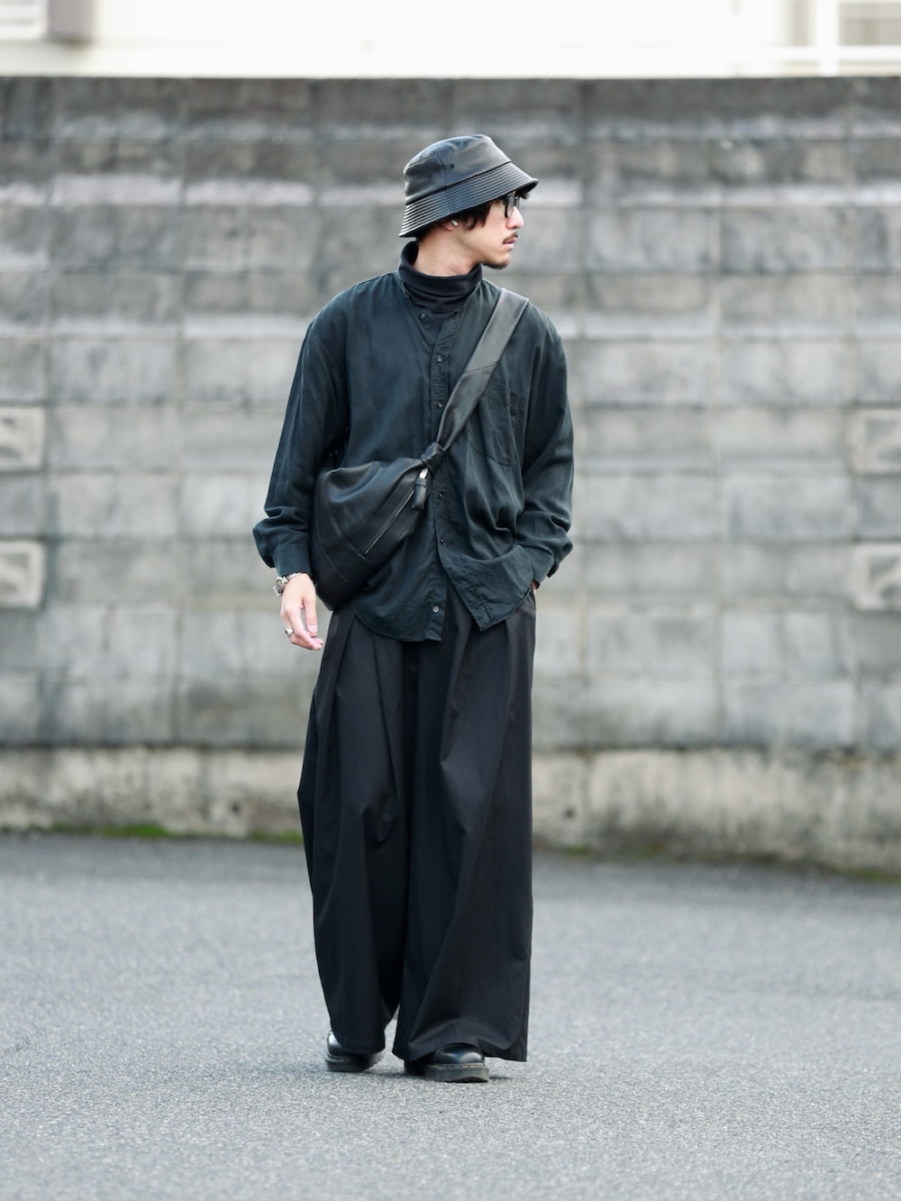 ブラック系のショルダーバッグ、ブラック系のパンツ、ブラック系のブーツを着用したメンズの秋コーディネートの2枚目の写真