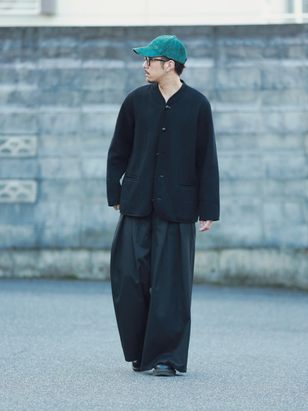 ブラック系のパンツ、ブラック系のシューズ、グリーン系のキャップを着用したメンズの秋コーディネートの3枚目の写真