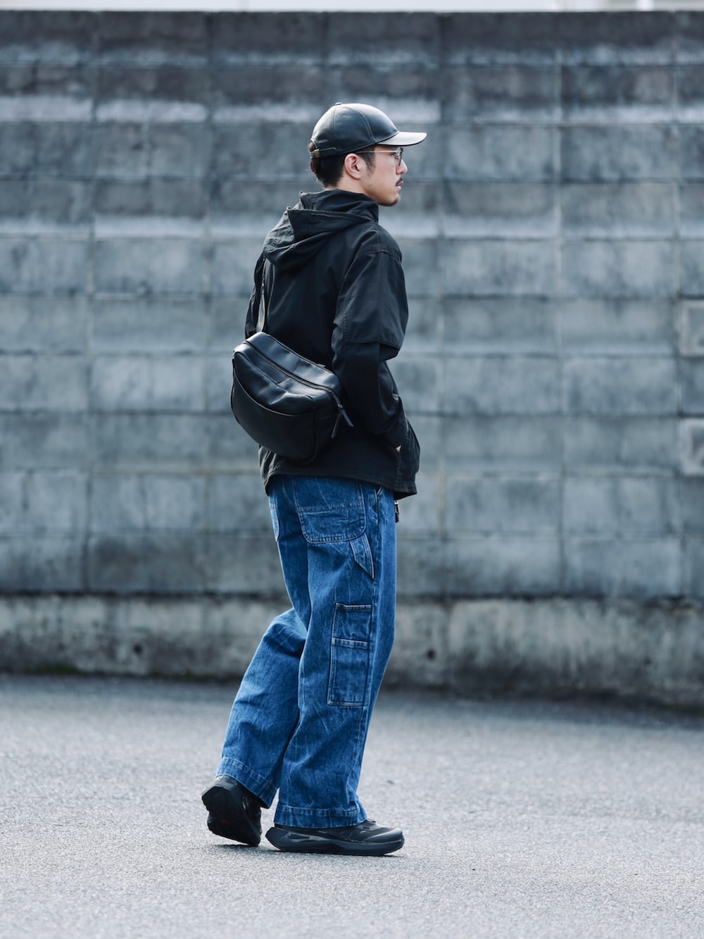 ブルー系のデニムパンツ、ブラック系のショルダーバッグ、ブラック系のスニーカーを着用したメンズの秋コーディネートの2枚目の写真