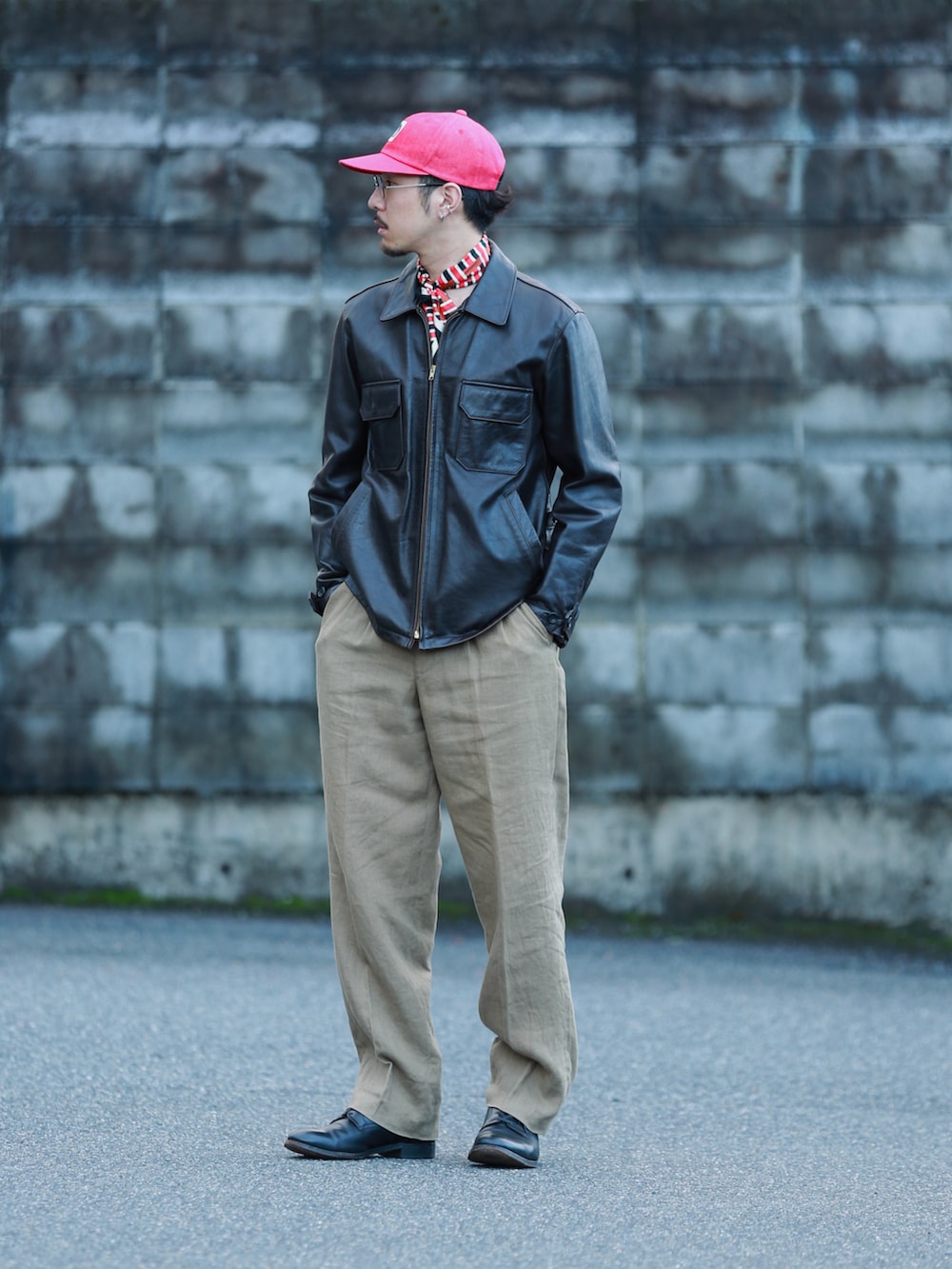 ブラウン系のハンドバッグ、ブラック系のドレスシューズ、レッド系のキャップを着用したメンズの秋コーディネートの3枚目の写真