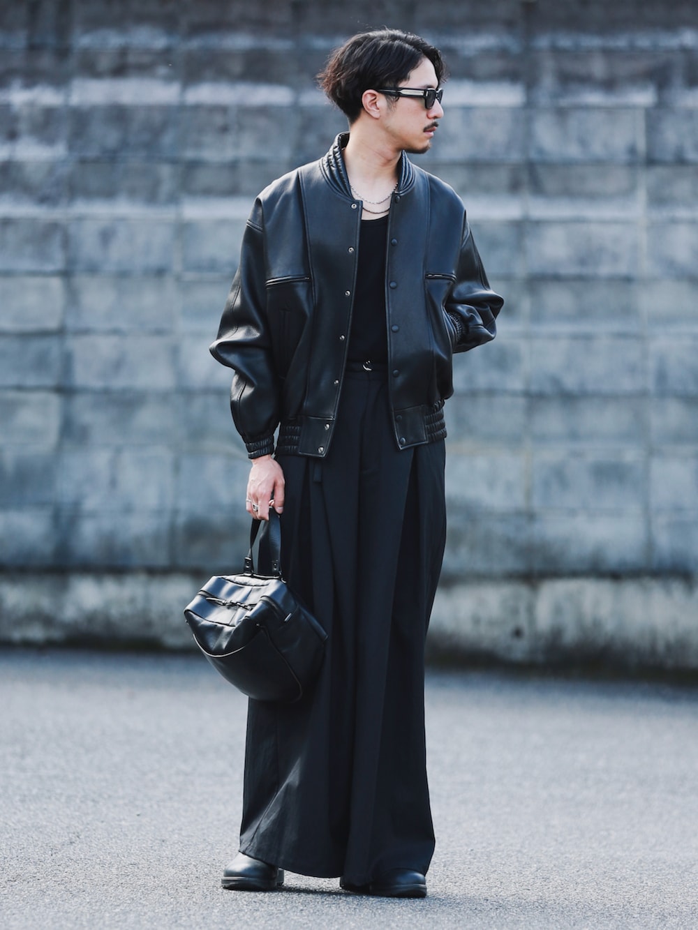 ブラック系のその他アウター、ブラック系のパンツ、ブラック系のショルダーバッグを着用したメンズの秋コーディネートの2枚目の写真