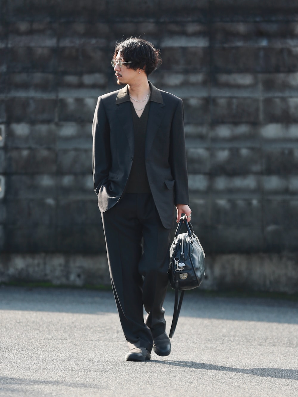 ブラウン系のニット/セーター、ブラック系のバッグ、グレー系のスリッポンを着用したメンズの冬コーディネートの2枚目の写真