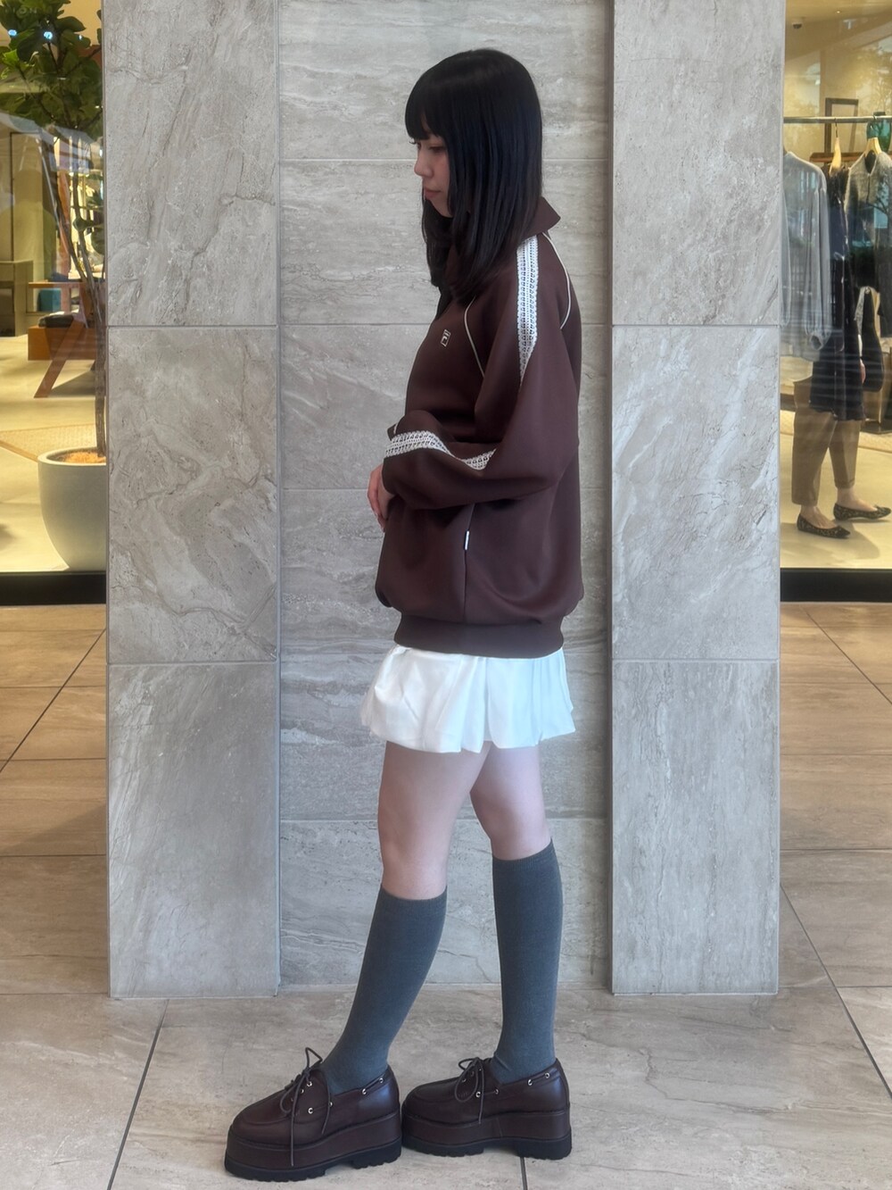 ブラウン系のTシャツ/カットソー、ホワイト系のスカート、ブラウン系のローファーを着用したレディースの秋コーディネートの4枚目の写真