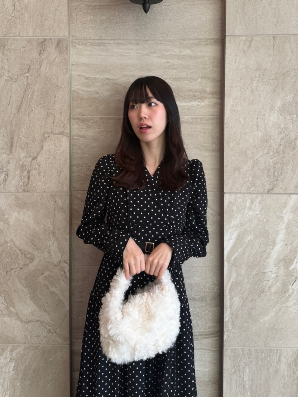 ブラック系のワンピース、ホワイト系のハンドバッグ、ブラック系のパンプスを着用したレディースの秋コーディネートの5枚目の写真