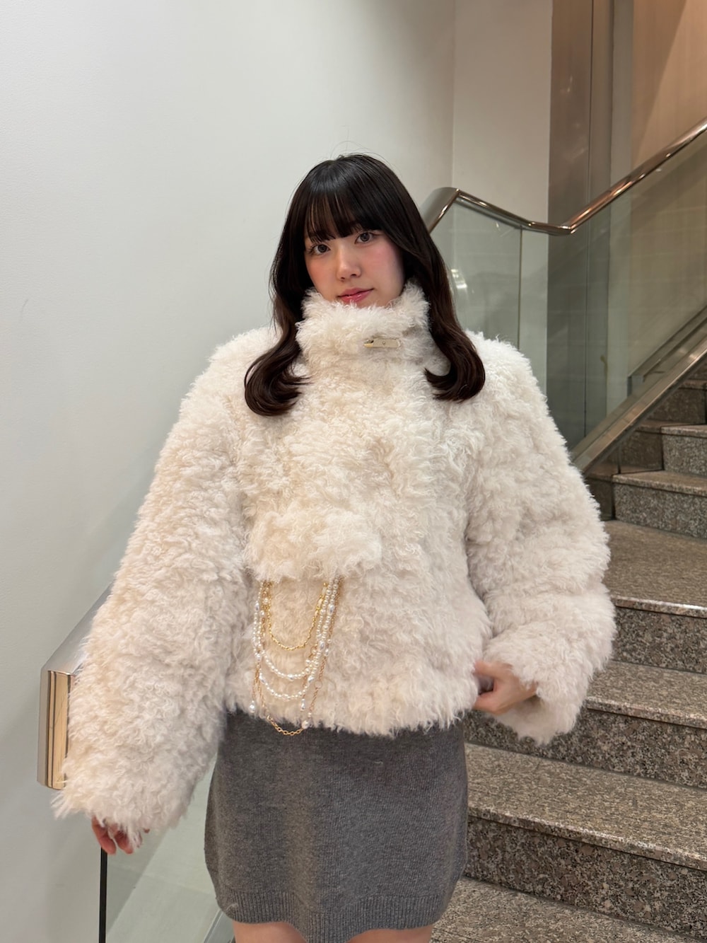 ホワイト系のブルゾン、グレー系のワンピース、ブラック系のブーツを着用したレディースの秋コーディネートの8枚目の写真