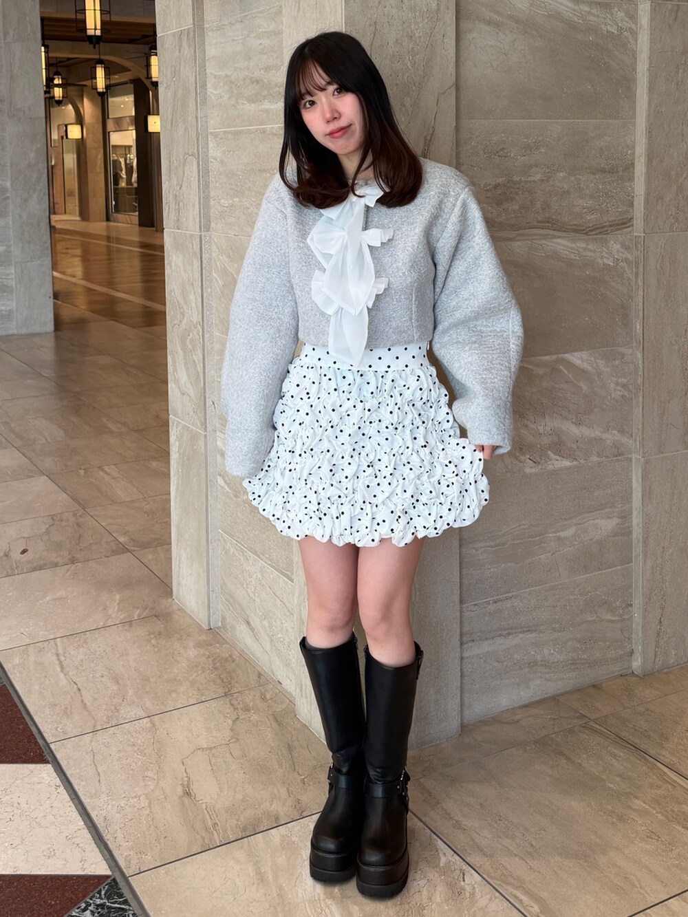 グレー系のブルゾン、ホワイト系のスカート、ブラック系のブーツを着用したレディースの冬コーディネートの2枚目の写真