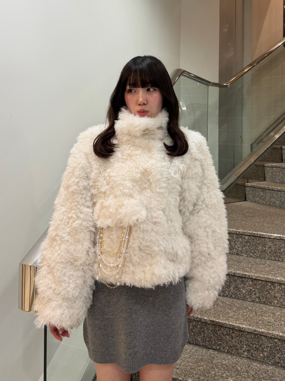 ホワイト系のブルゾン、グレー系のワンピース、ブラック系のブーツを着用したレディースの秋コーディネートの9枚目の写真