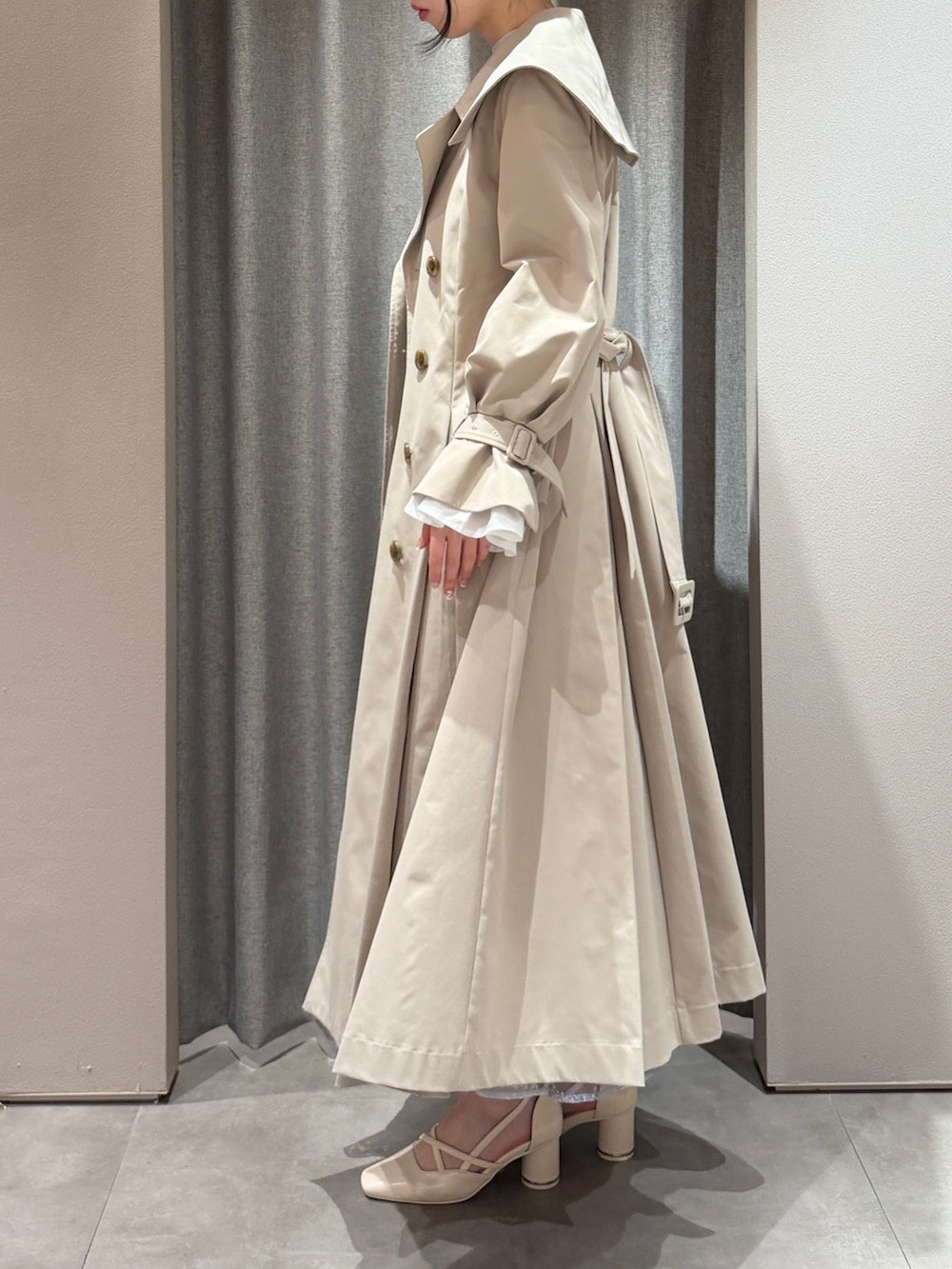 ベージュ系のトレンチコート、ブルー系のドレス、ホワイト系のサンダルを着用したレディースの春コーディネートの2枚目の写真