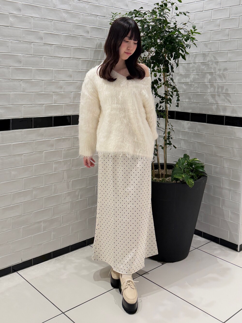 ホワイト系のニット/セーター、ホワイト系のスカート、ホワイト系のローファーを着用したレディースの秋コーディネートの2枚目の写真