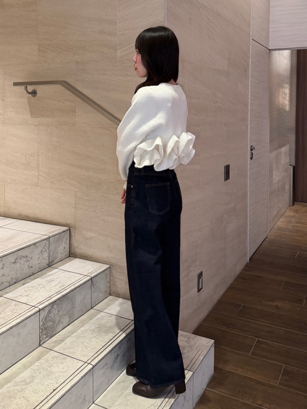 ホワイト系のノーカラージャケット、ブルー系のデニムパンツ、ブラウン系のブーツを着用したレディースの冬コーディネートの3枚目の写真