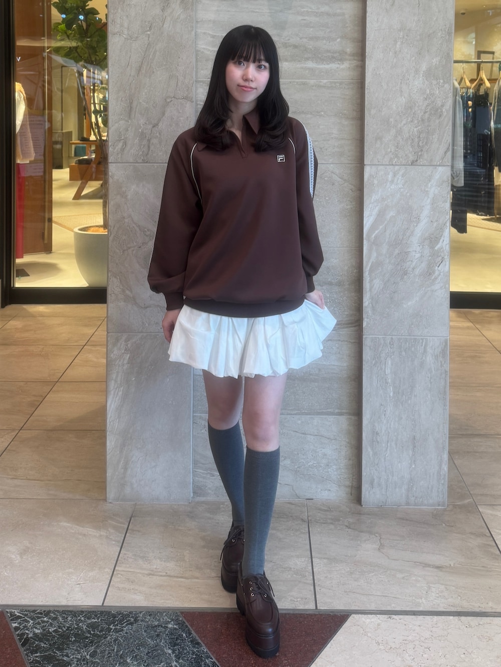 ブラウン系のTシャツ/カットソー、ホワイト系のスカート、ブラウン系のローファーを着用したレディースの秋コーディネートの2枚目の写真