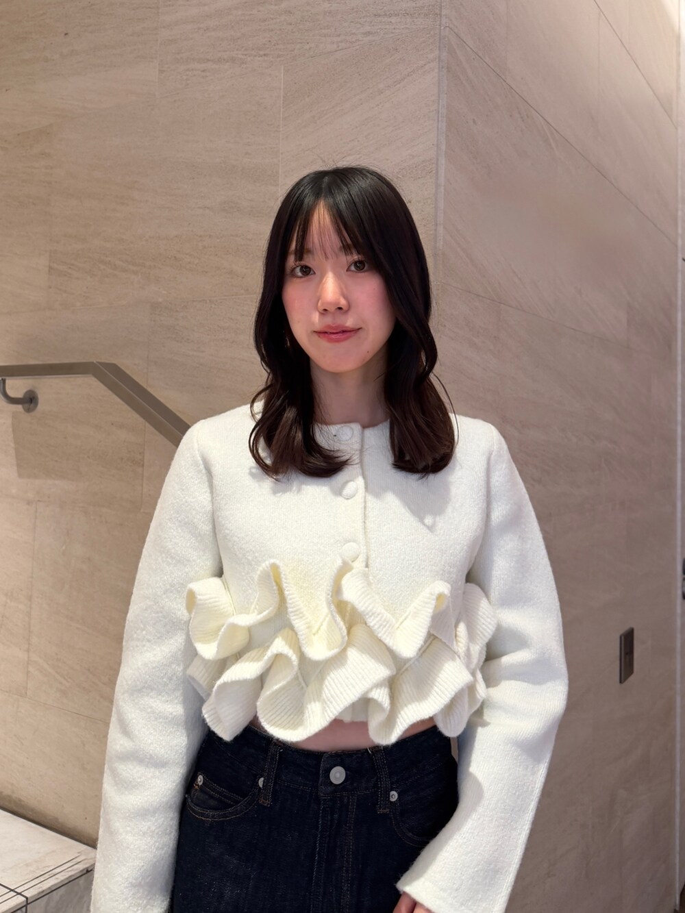 ホワイト系のノーカラージャケット、ブルー系のデニムパンツ、ブラウン系のブーツを着用したレディースの冬コーディネートの6枚目の写真