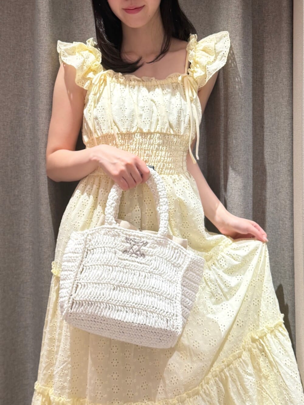 ホワイト系のかごバッグ、イエロー系のワンピース、ホワイト系のサンダルを着用したレディースの夏コーディネートの5枚目の写真